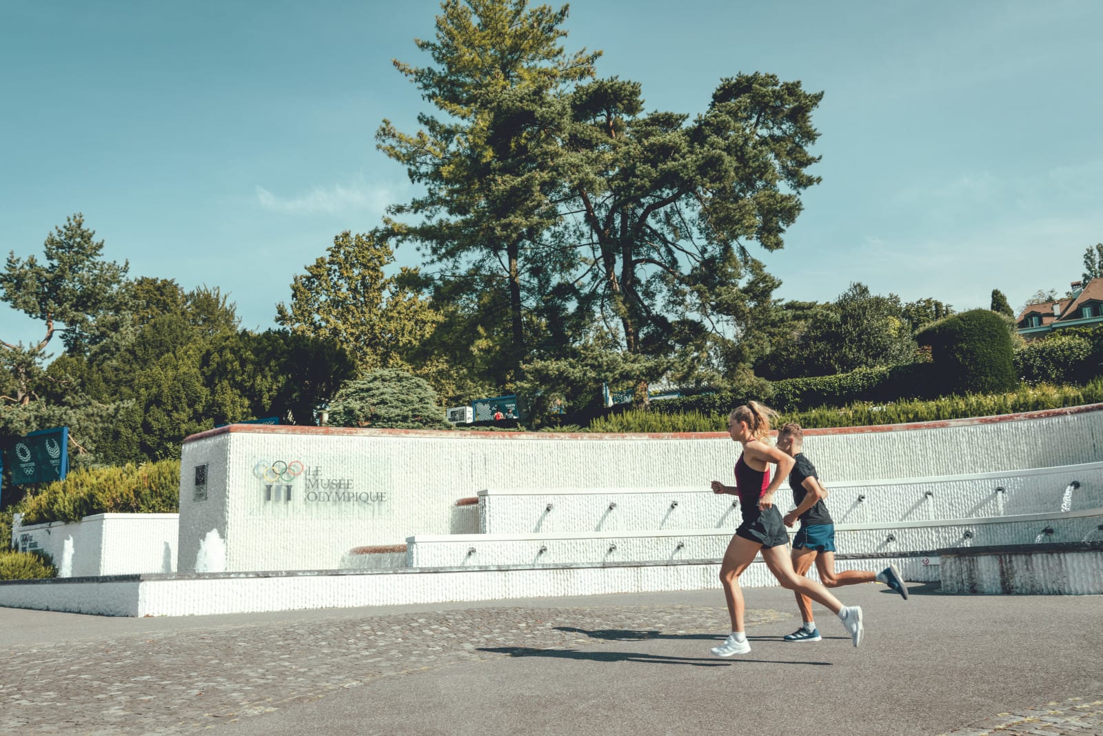 Lausanne : les activités outdoors de l’été - © Course a pied devant la fontaine du Musee Olympique. campagne ST ete 2022 - ville sportive / olympique.